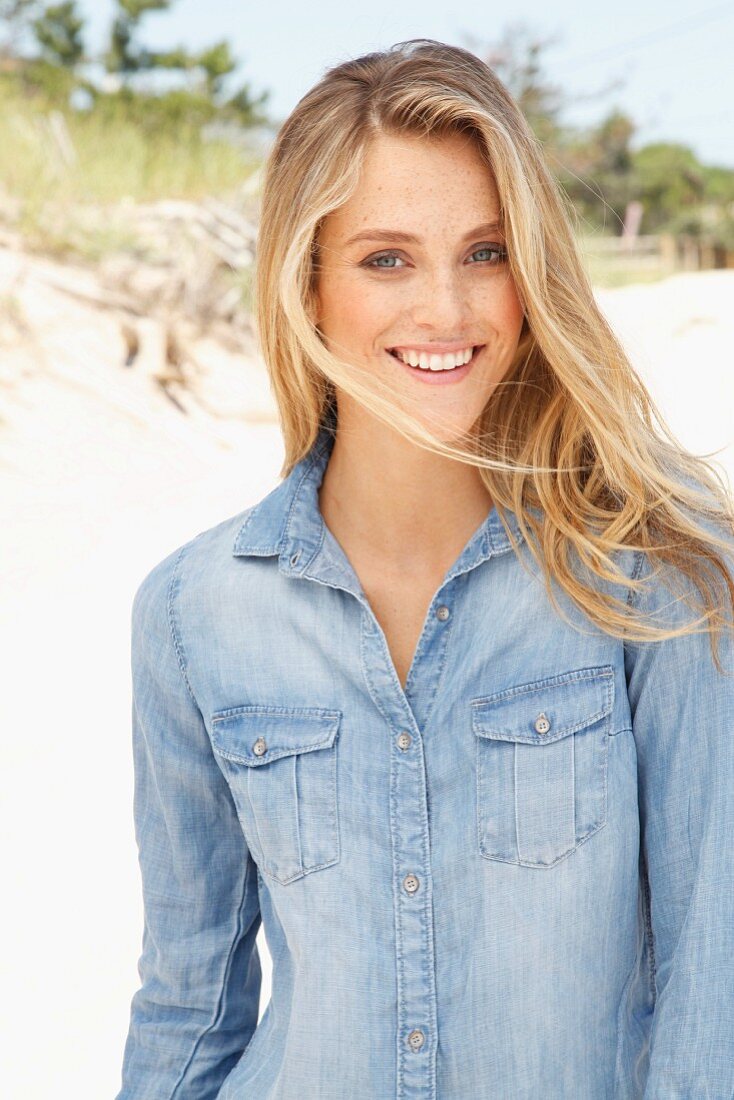 Junge Frau in Jeanshemd am Strand