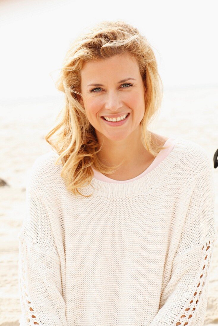 A blonde woman wearing a white knitted jumper