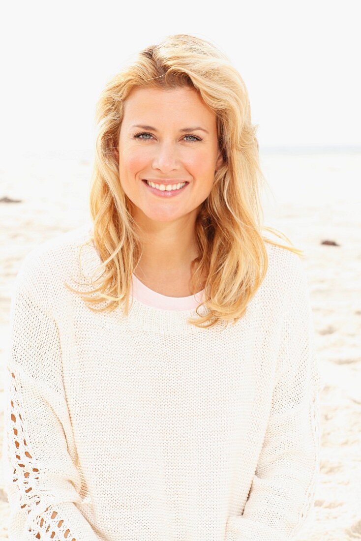 A blonde woman wearing a white knitted jumper