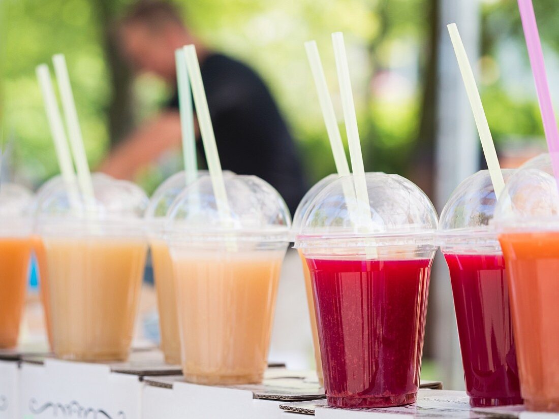 Various juices in plastic cups at a market stall