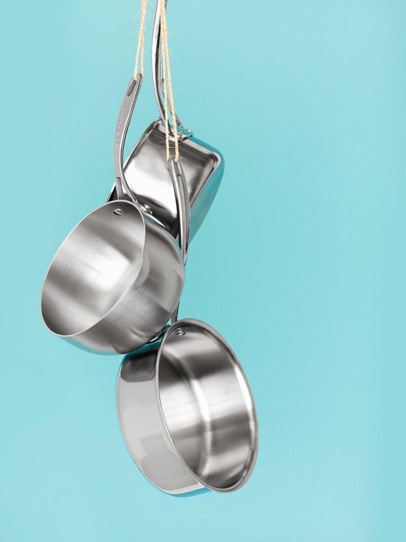 Three stainless steel pans hanging up