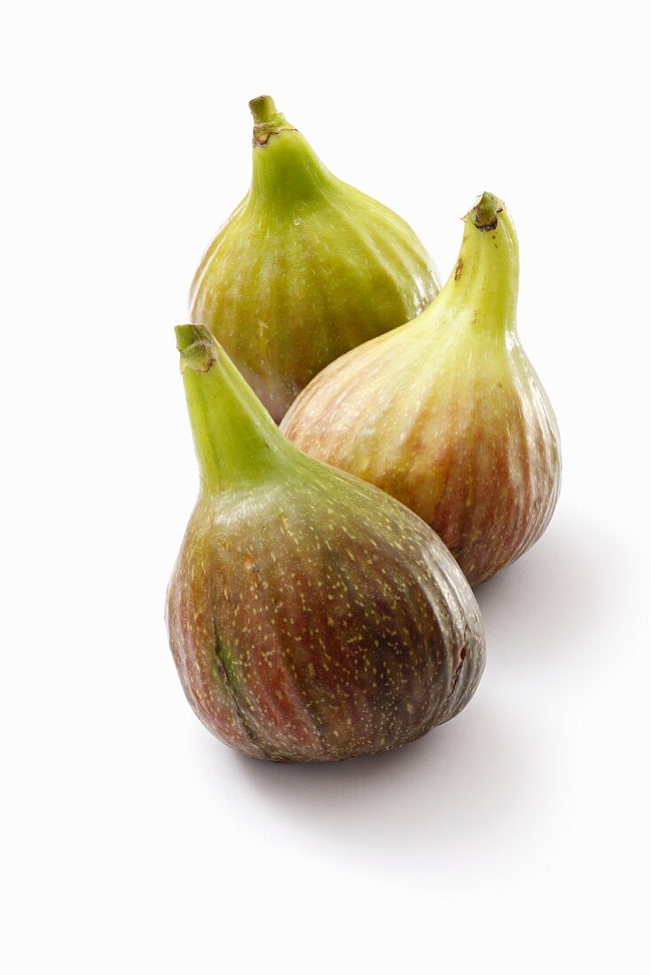 Three fresh figs on a white surface