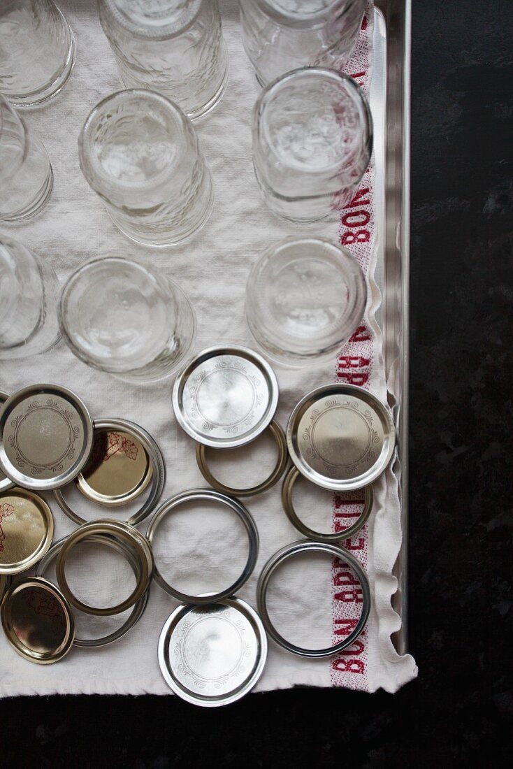 Jam jars and lids on a tray with a tea towel