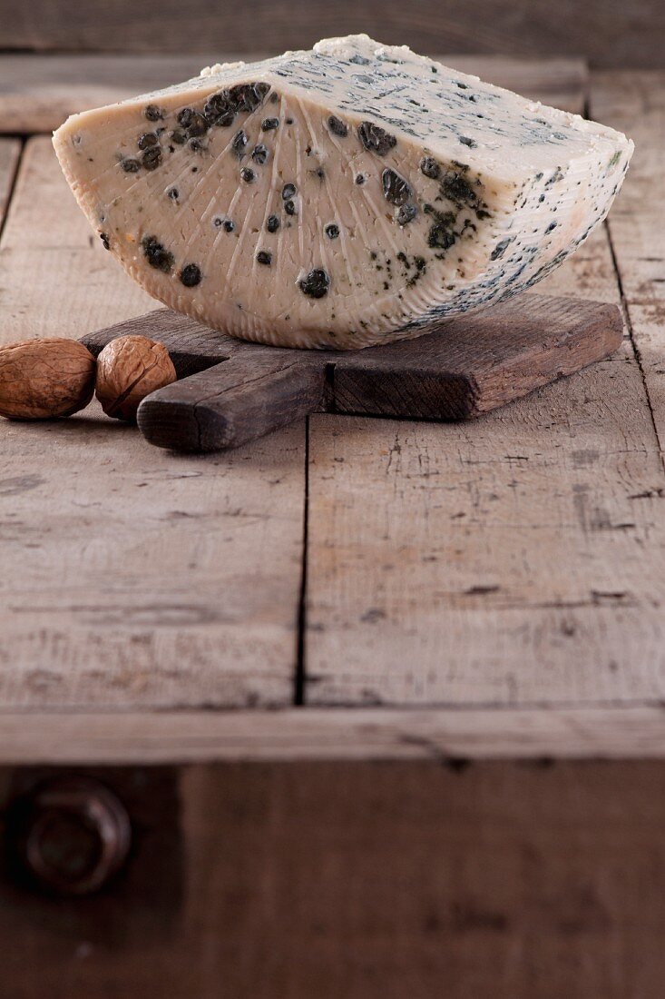A slice of blue cheese on a wooden board
