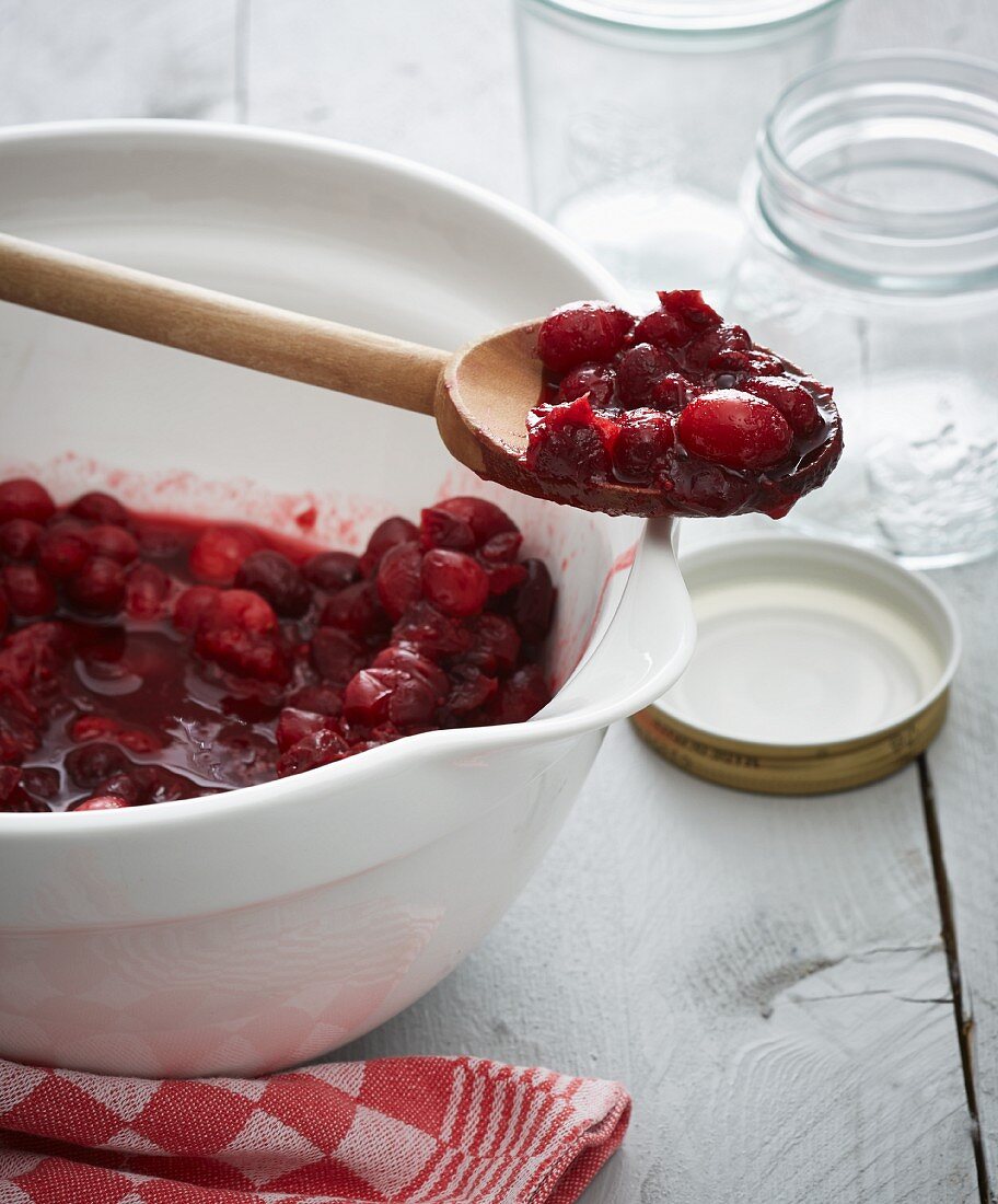 Lingonberry jam in a bowl and on a wooden spoon