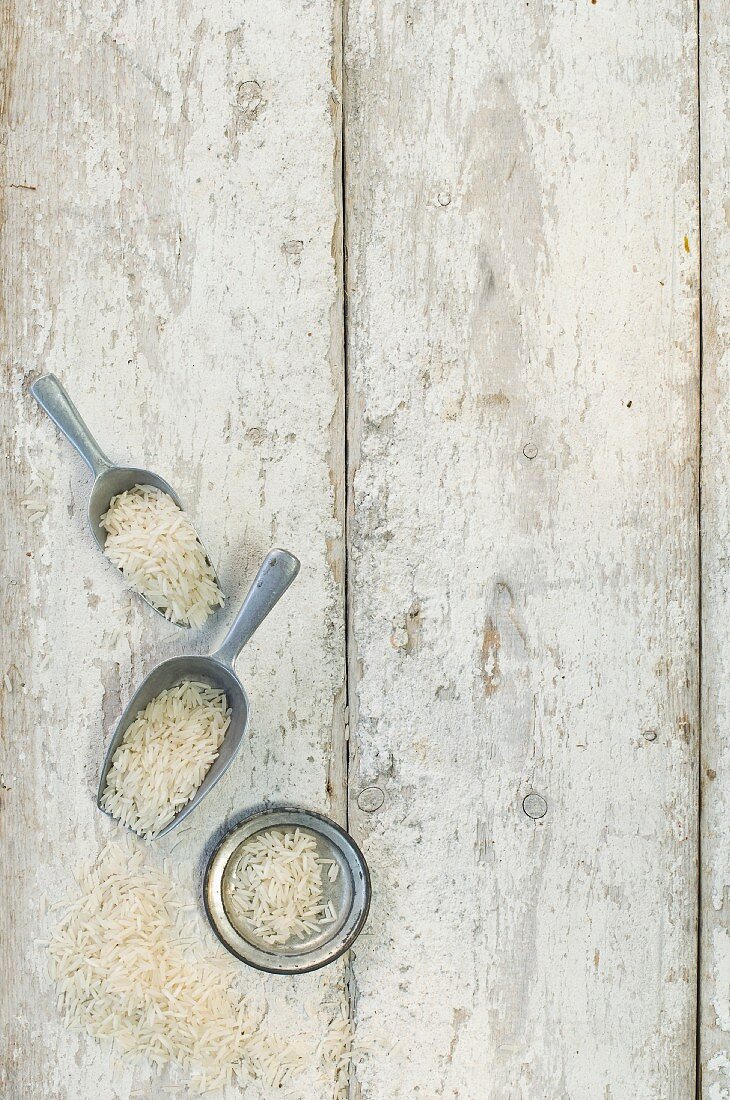 Rice in a bowl, on scoops and on a wooden surface