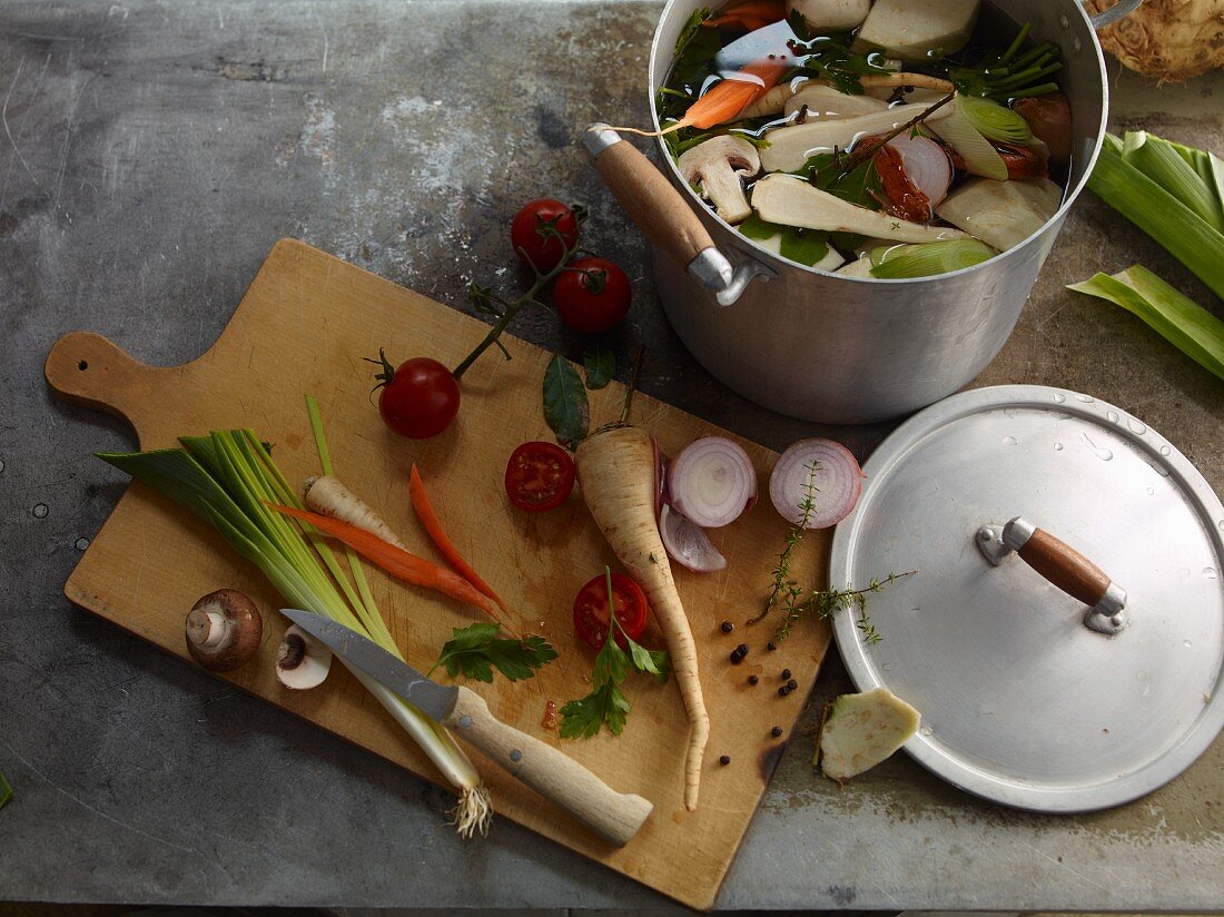 ingredients for vegetable stock on a wooden board and in a pot
