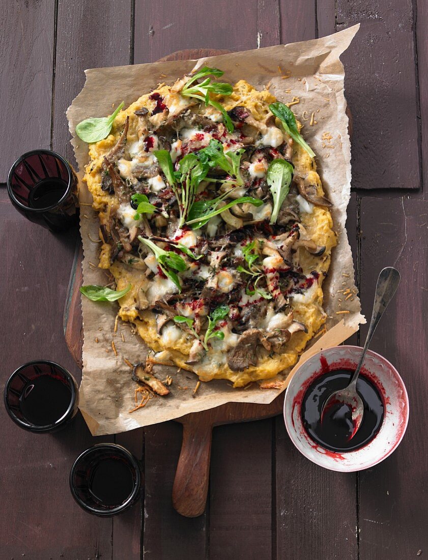 Polenta pizza with mushrooms and lamb's lettuce on baking paper