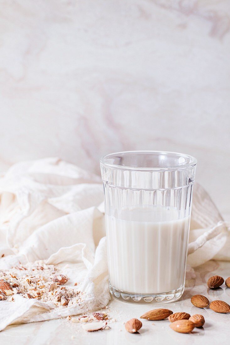 A glass of almond milk, next to whole and ground almonds