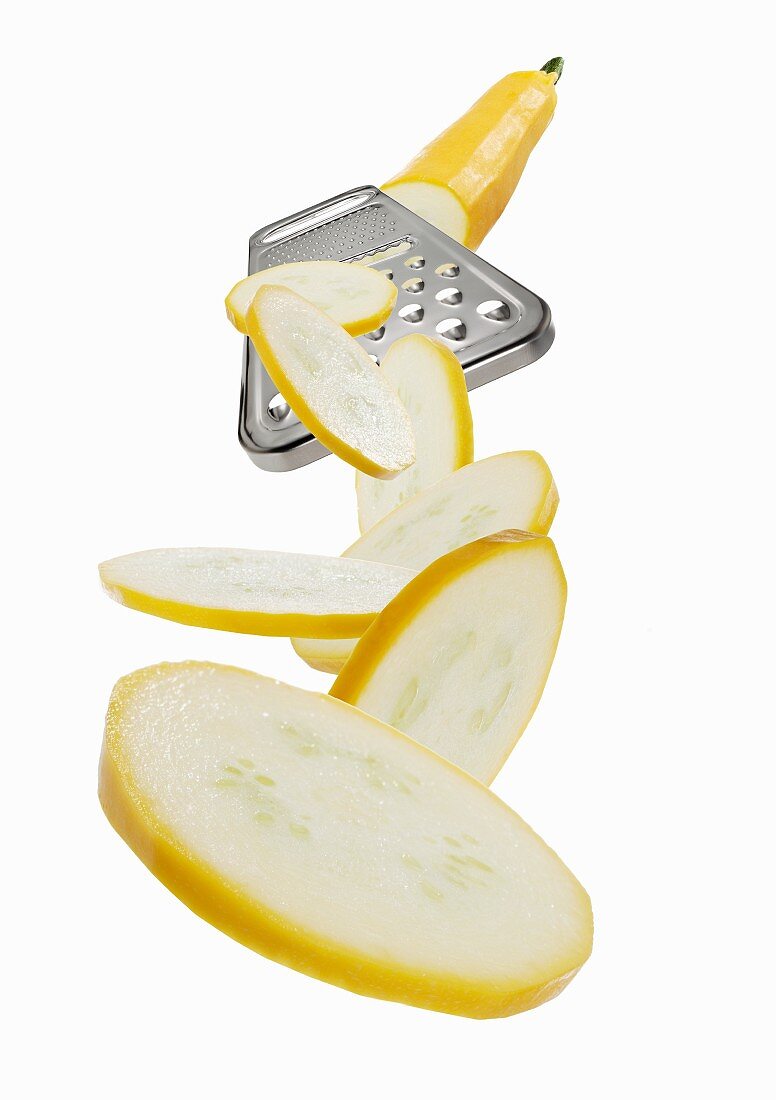 A vegetable grater with a yellow courgette slices
