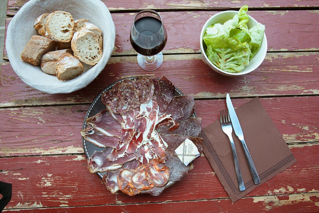 Rustikale Wurstplatte mit Brot, Rotwein und Kopfsalat