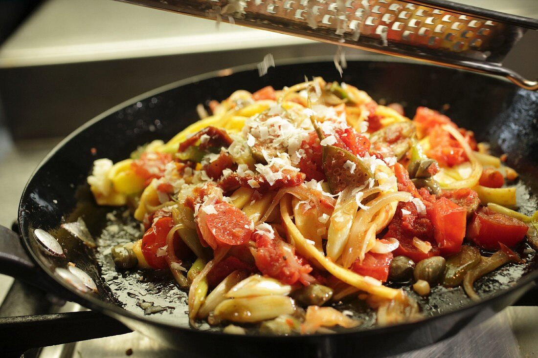 Parmesan auf Nudelgericht reiben