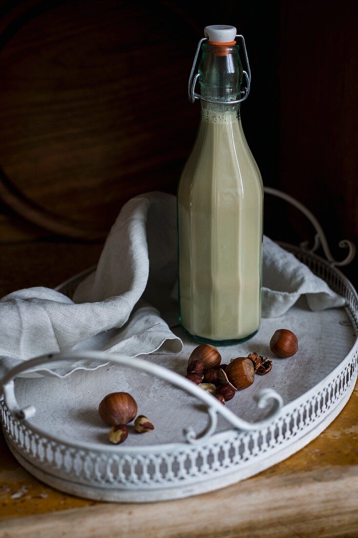 Vegan hazelnut milk in glass bottles on a vintage tray