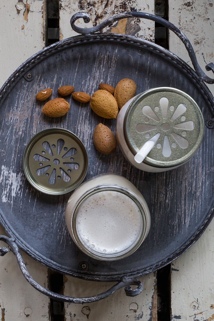 Vegan almond milk in glasses with straws and lids on a tray