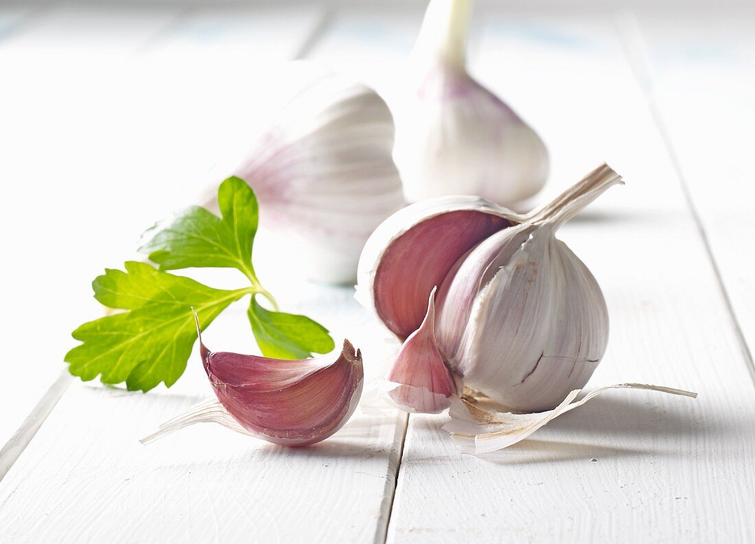 Bulbs of garlic on a white wooden surface