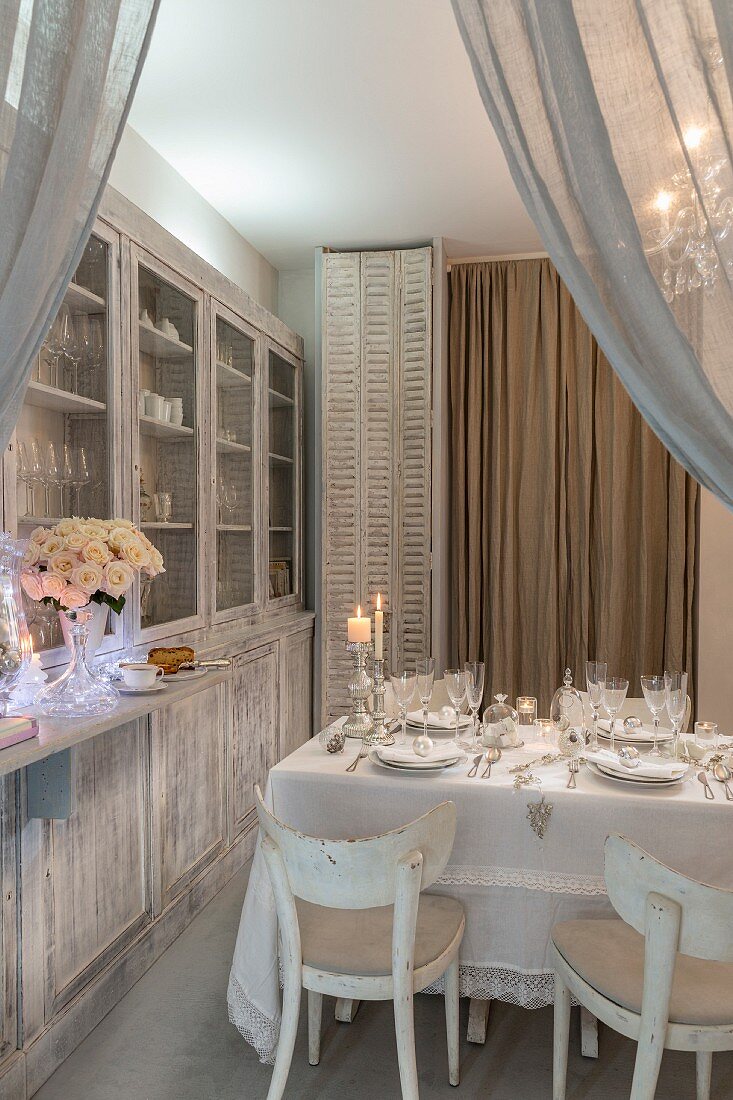 Set Christmas dininer table next to dresser in white shabby-chic interior