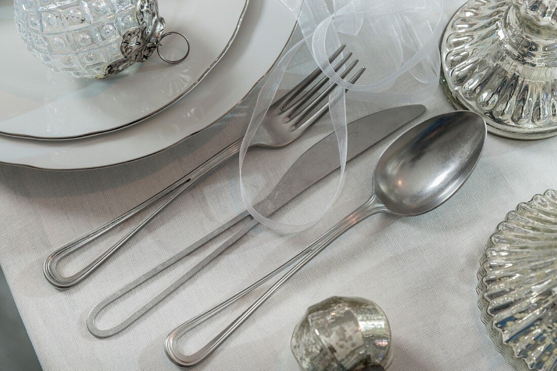 Silver cutlery with centres of handles removed on set table