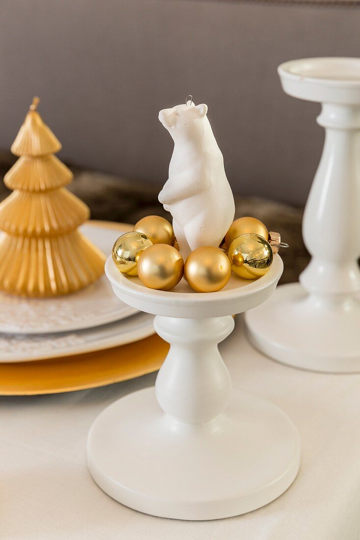 weiße Bärenfigur auf einem Kerzenständer mit goldenen Christbaumkugeln