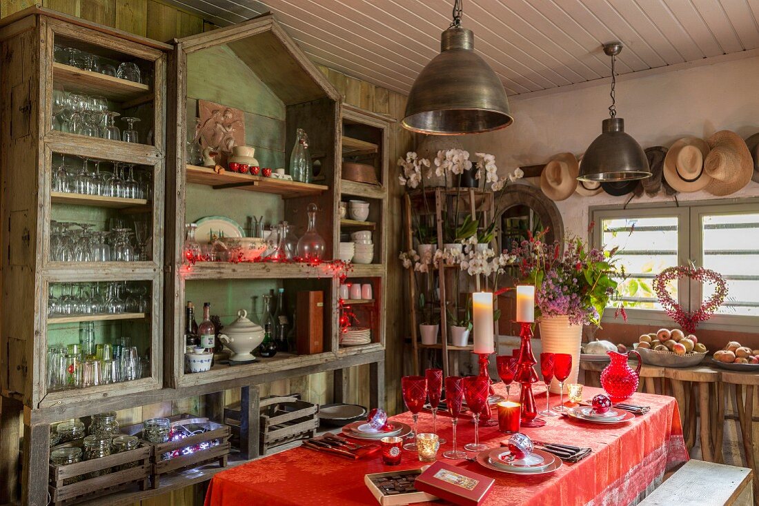 Christmas table set with red cloth and glasses in vintage interior in style of garden shed