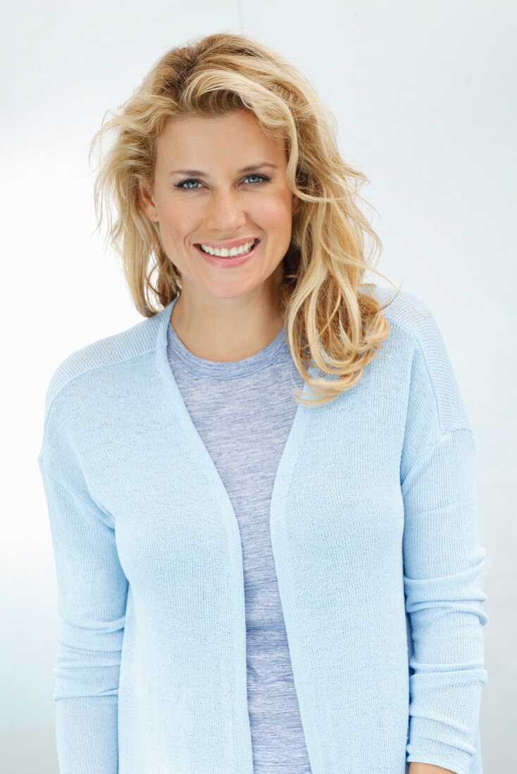 Blonde Frau in blauem Top und hellblauem Cardigan