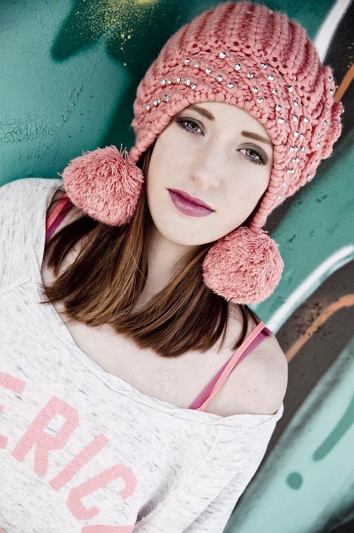 A young woman wearing a dusky pink knitted hat