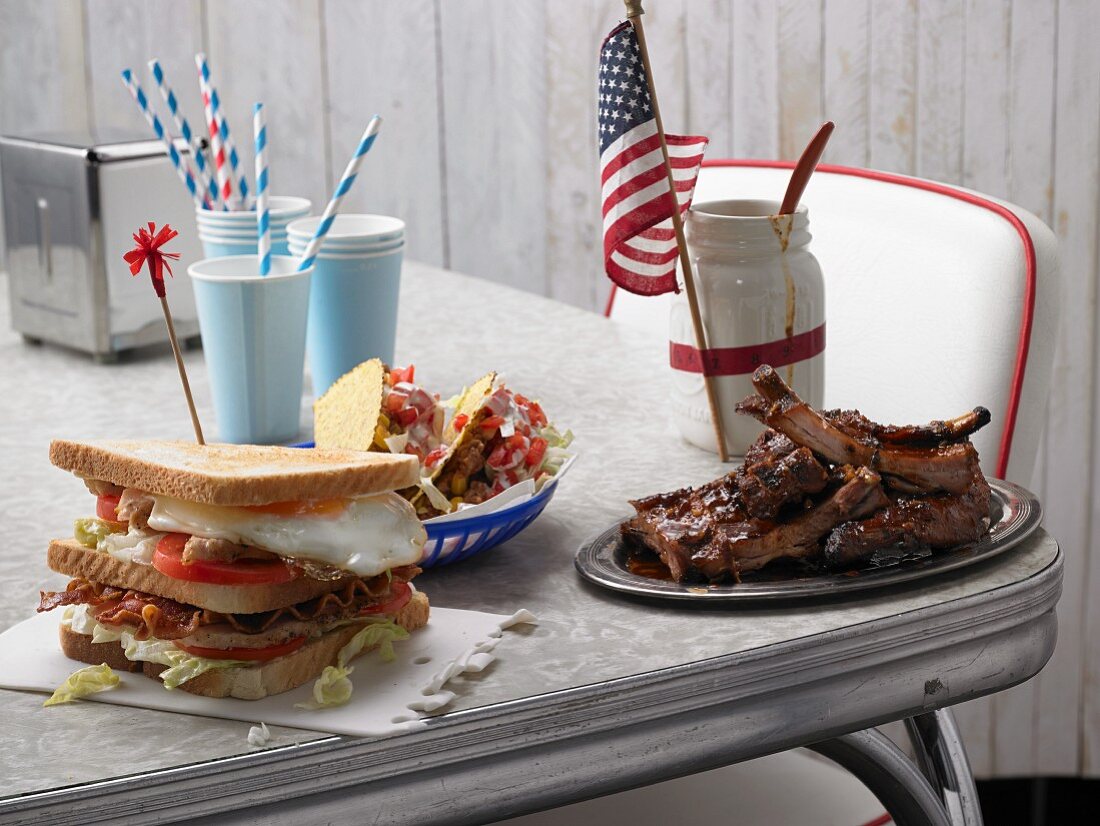 Clubsandwich, Taco-Shells & Spareribs auf Tisch (USA)