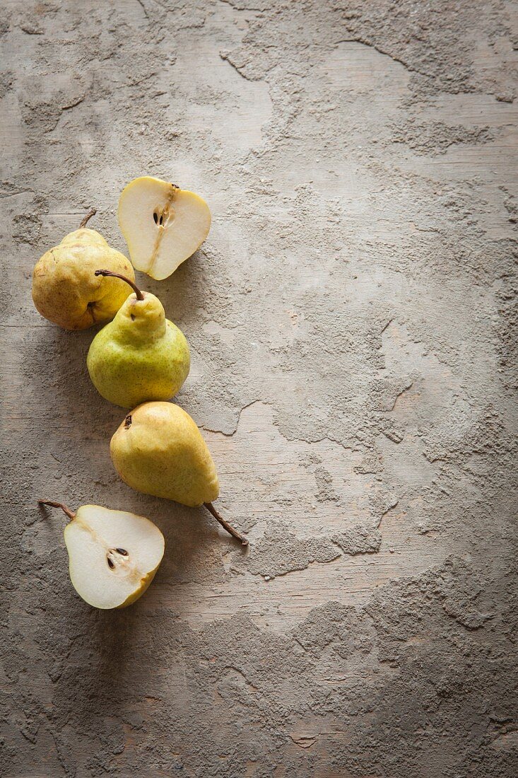 Pears and pear halves on a grey surface