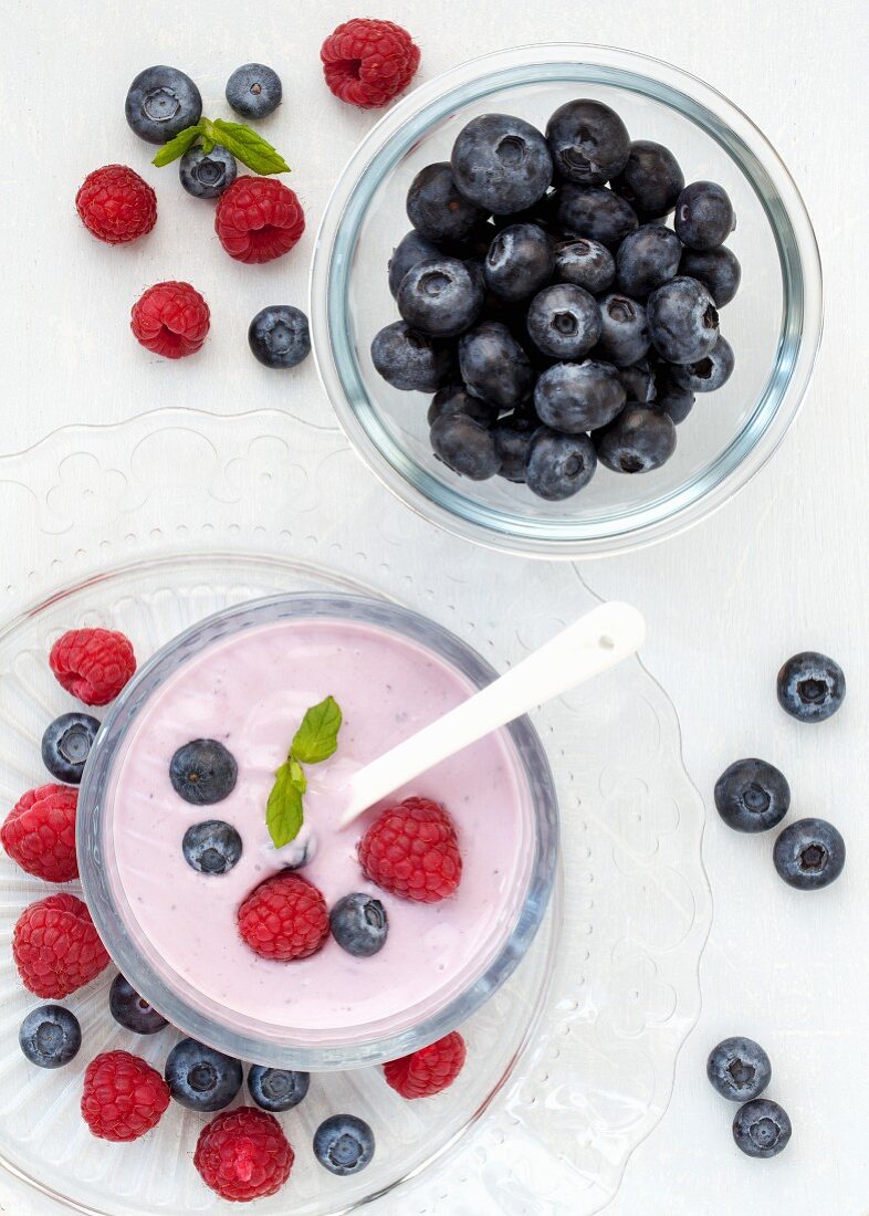 A bowl of fruity yoghurt with mixed raspberries and blueberries