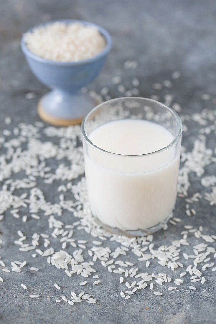 A glass of rice milk surrounded by grains of rice