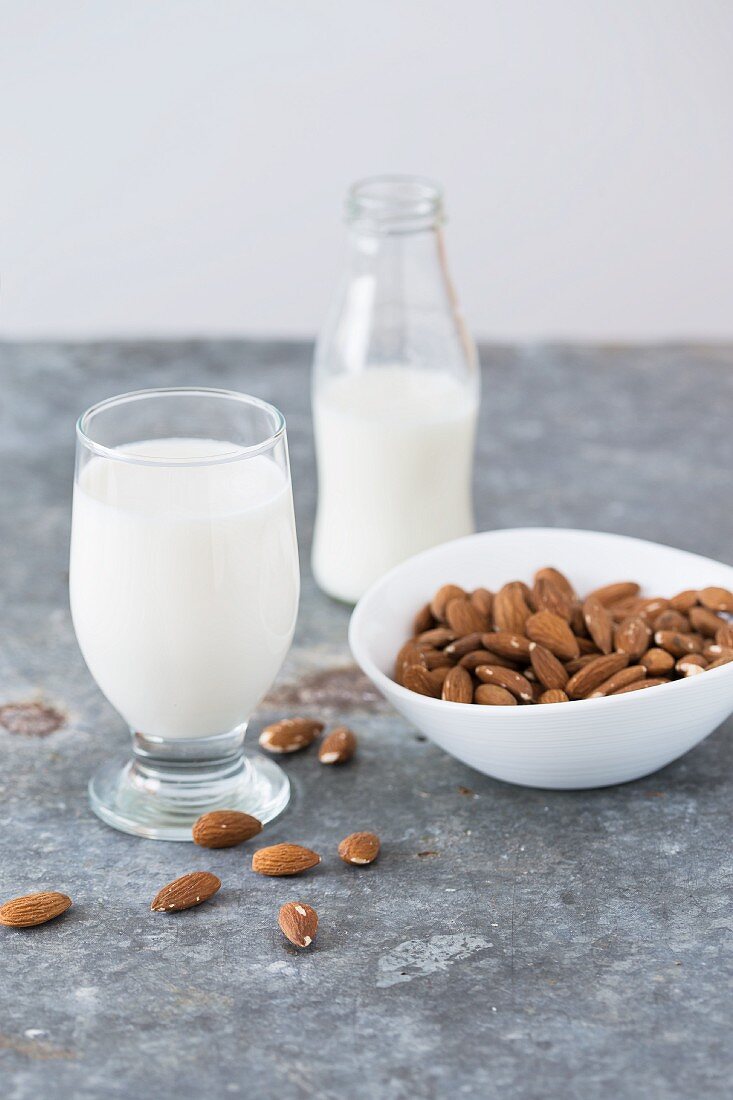 Whole almonds, and almond milk in a glass and in a bottle