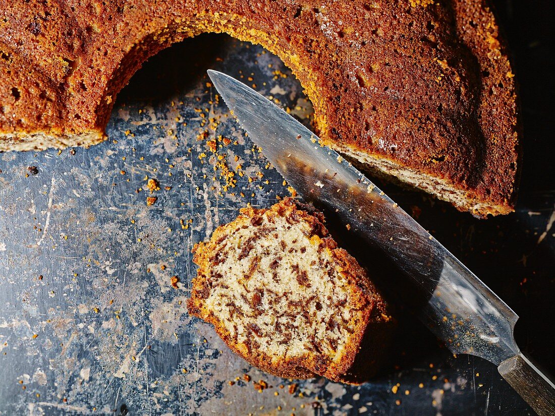 Angeschnittener Rum-Nuss-Schokoladenkuchen mit Messer auf Backblech