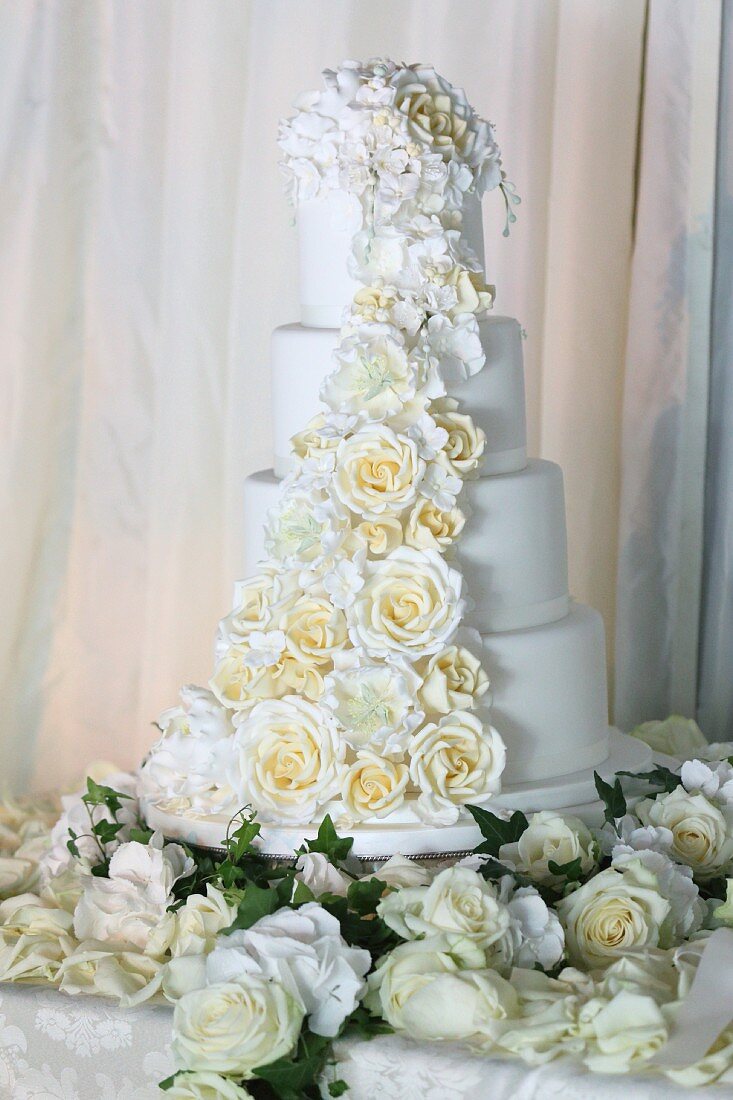 Multi-tiered, white wedding cake romantically decorated with roses