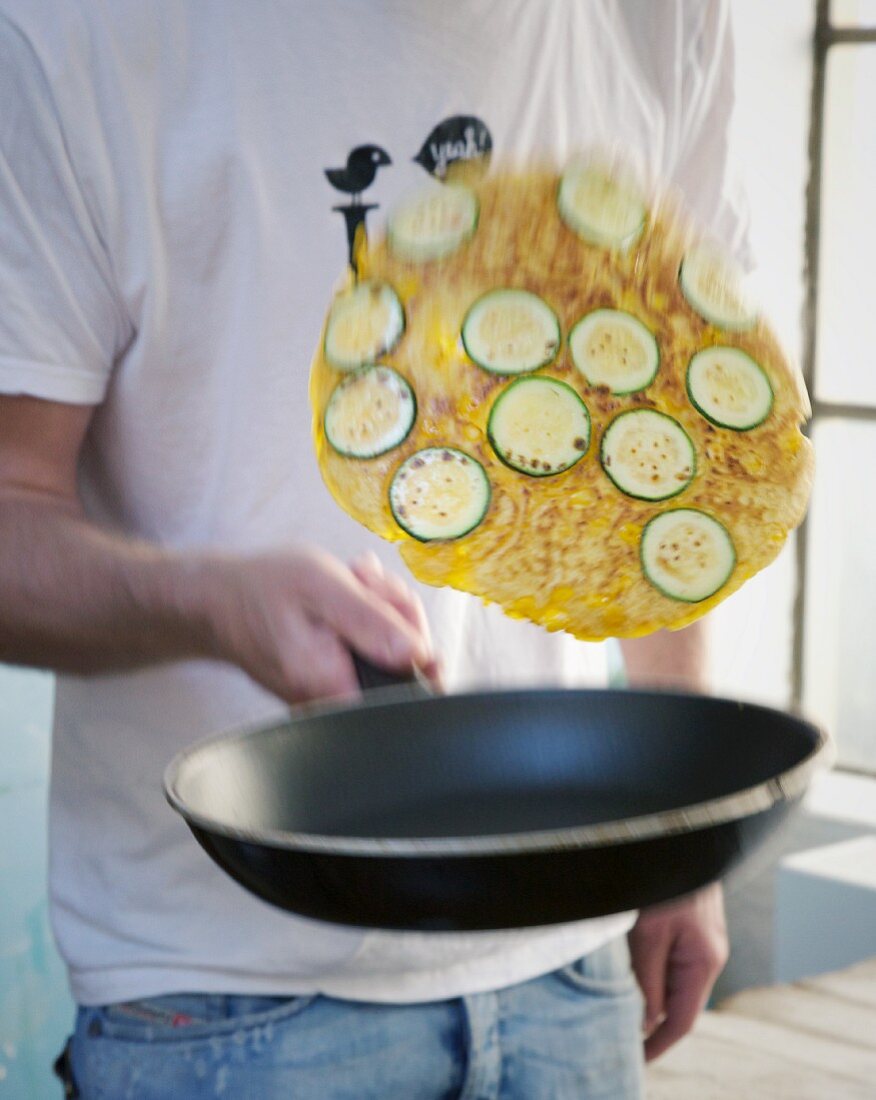 A pancake with courgette slices being flipped