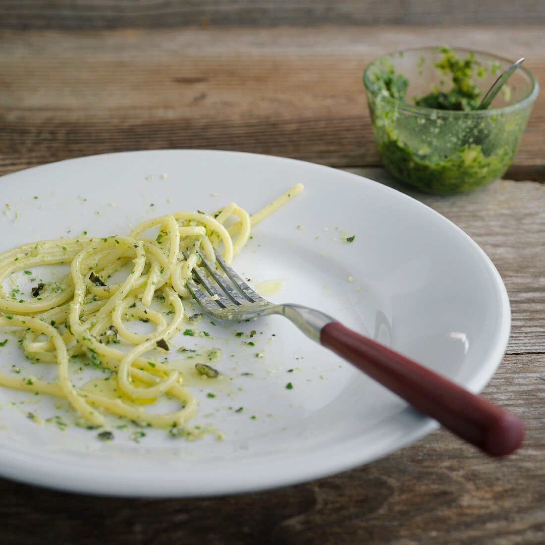 The remains of spaghetti with pumpkin seed pesto on a plate