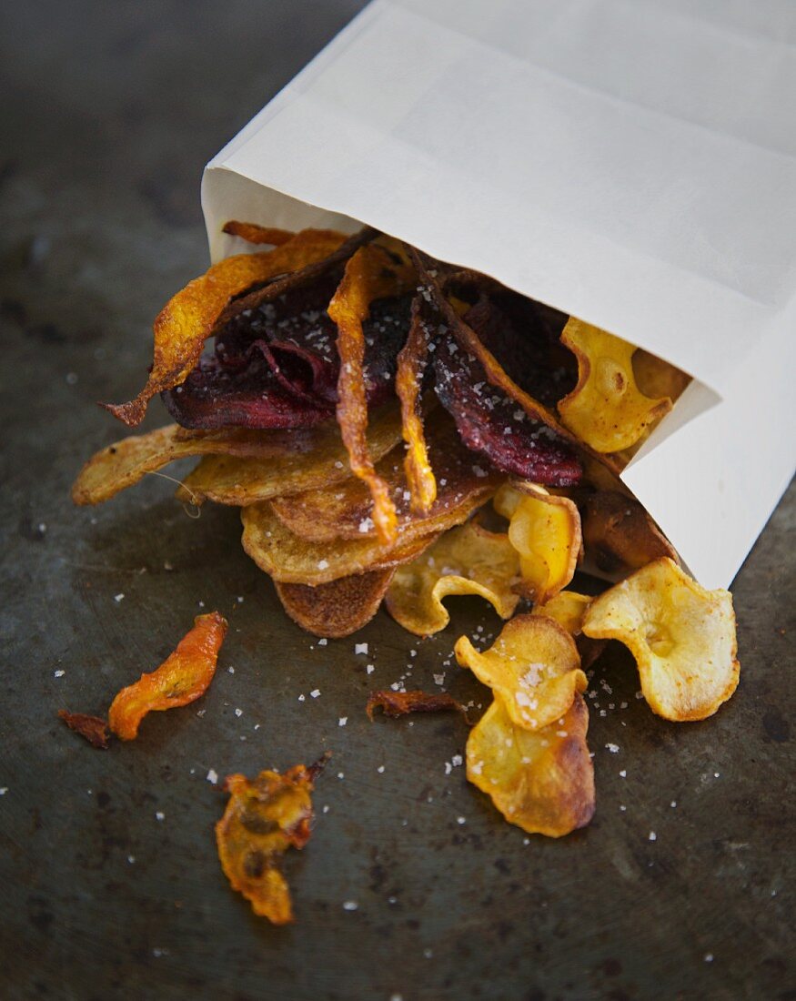 Colourful vegetable crisps with salt and a paper bag