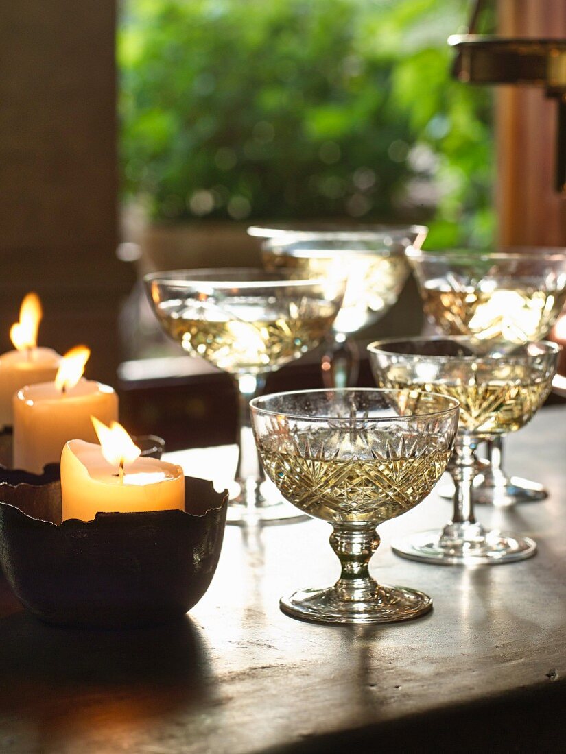Champagner in Kristallkelchen neben brennenden Kerzen