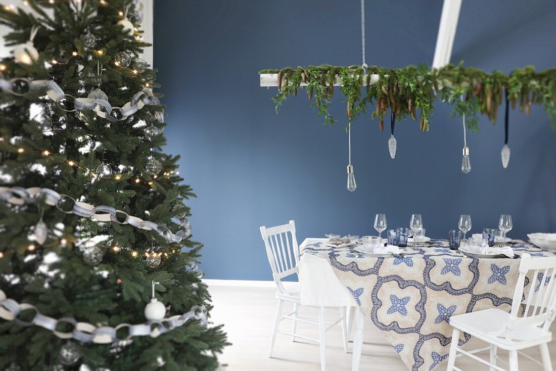 Christmas dining table set in blue and white next to decorated Christmas tree