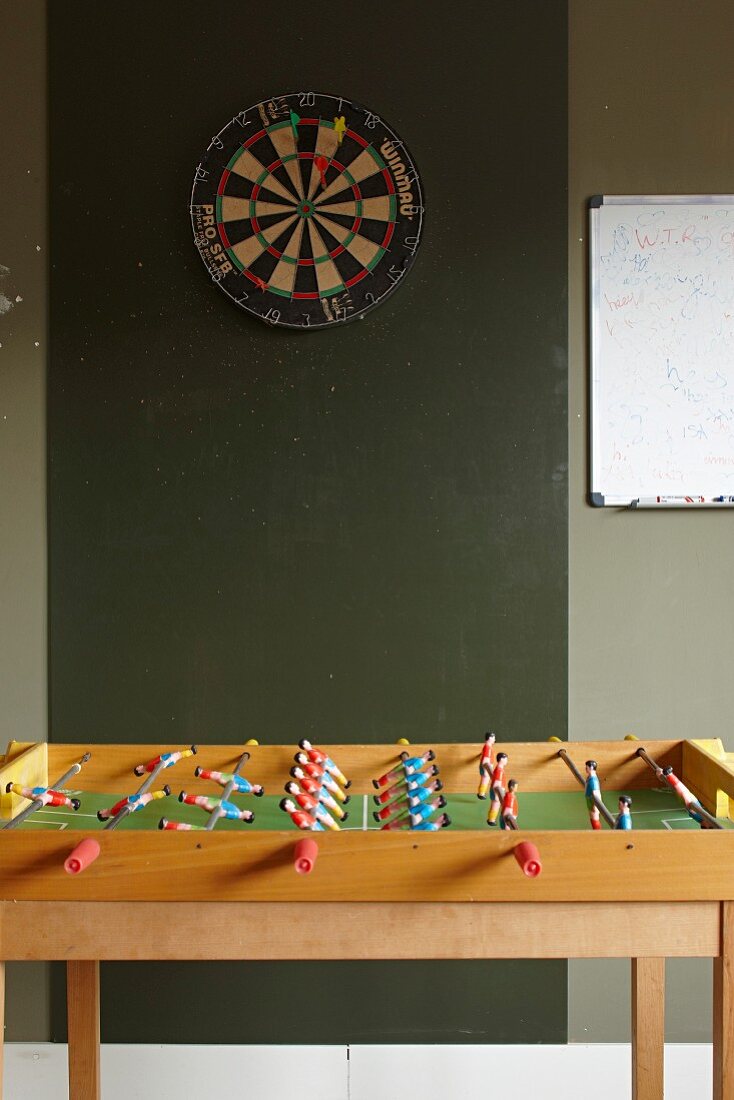 Table football table below darts board on green wall