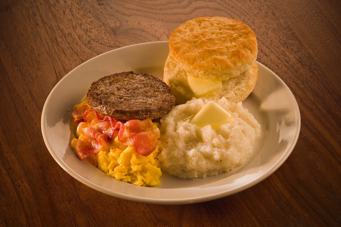Scrambled eggs with bacon, sausage, grits and biscuit (USA)