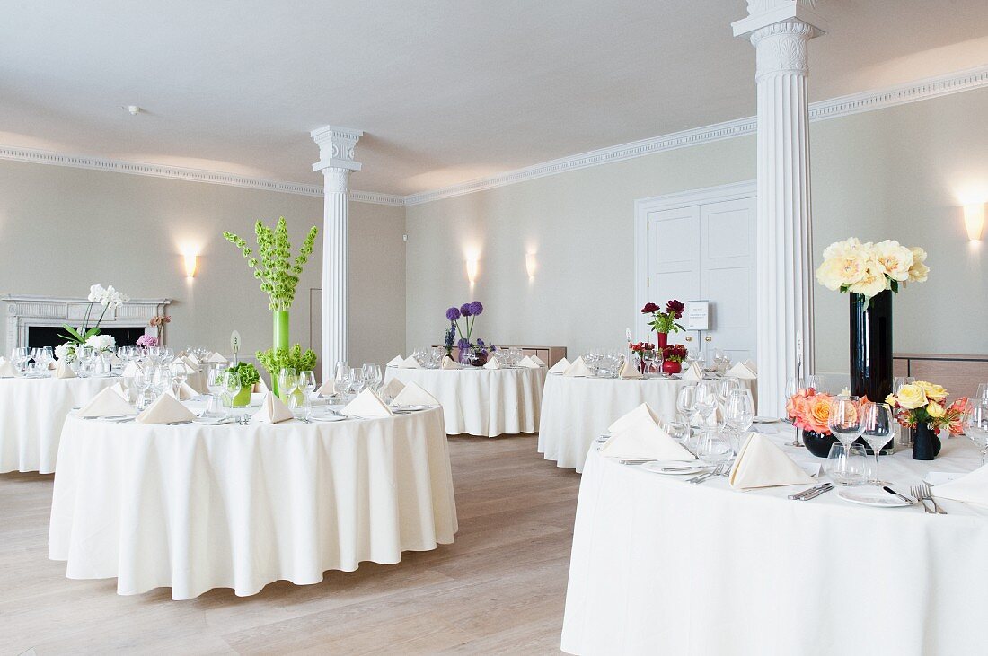 Festlich gedeckte Hochzeitstische in Raum mit weissen Säulen