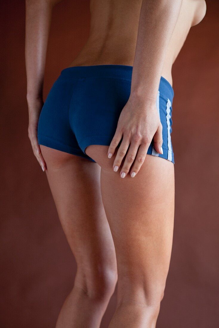 A woman wearing tight, blue, sporty shorts with her hands on her bottom