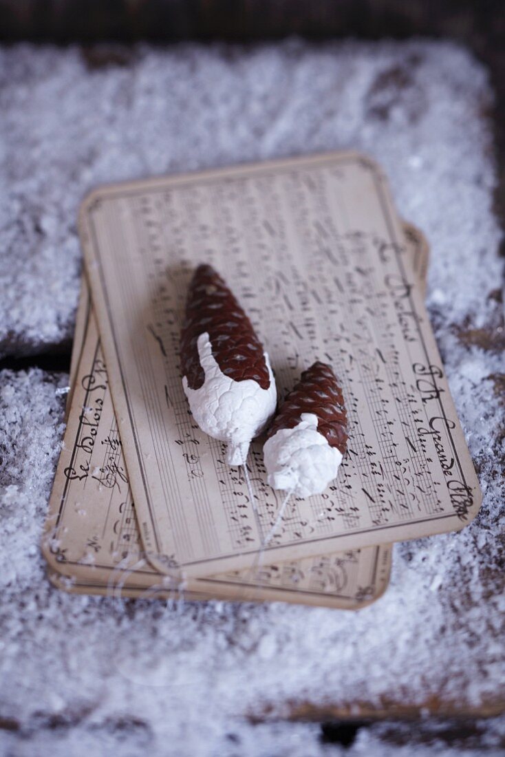 Pine cones decorated with white paint on old fashioned sheet music
