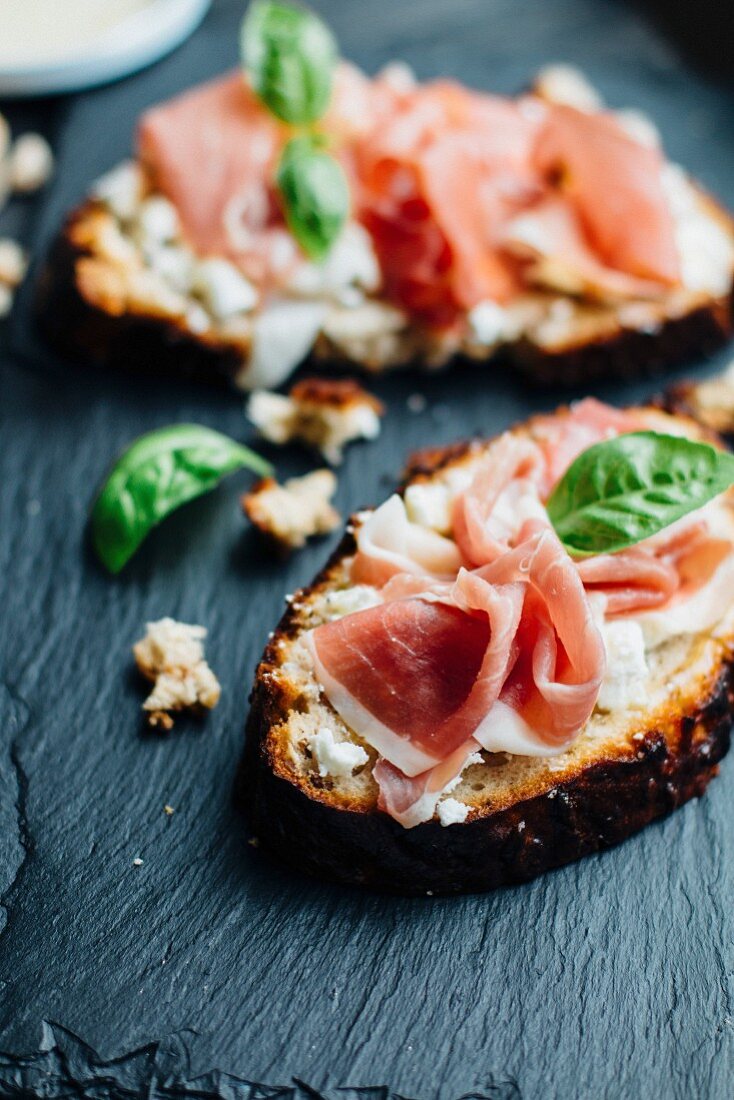 Open sandwiches topped with Parma ham and basil