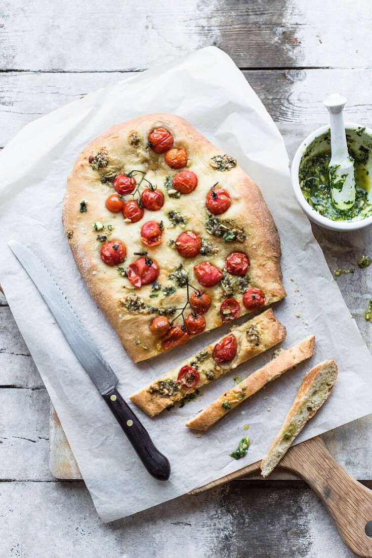 Focaccia mit Tomaten und Pesto, angeschnitten (Draufsicht)