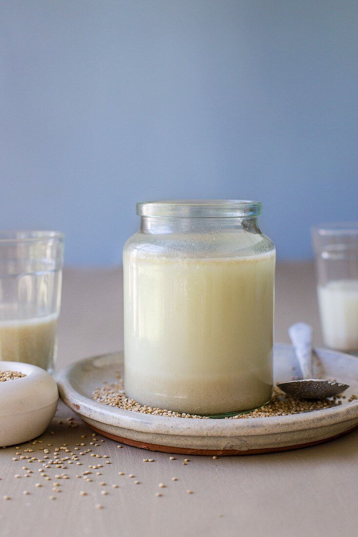 Quinoamilch in grossem Glas mit verstreuten Quinoakörnern