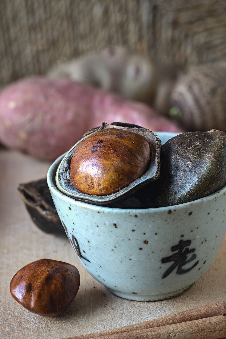 Frische Jengkol-Früchte im Schälchen vor Süsskartoffel und Topinambur