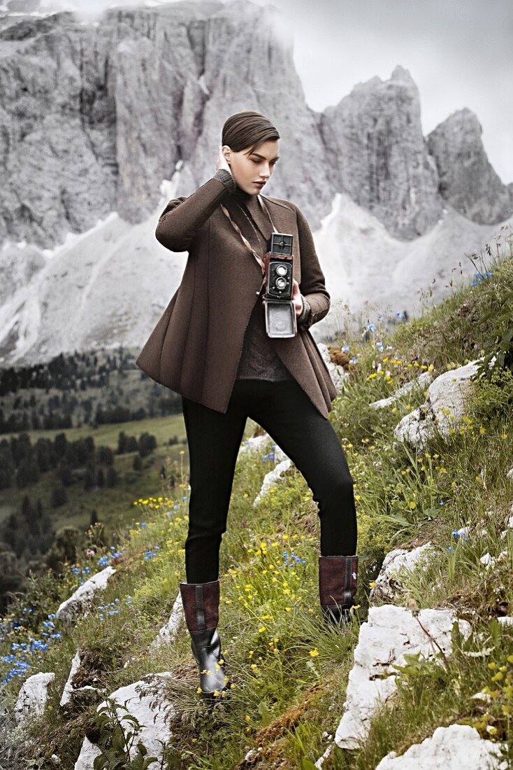 A short-haired woman wearing a collarless jacket, a jumper, stirrup trousers and boots