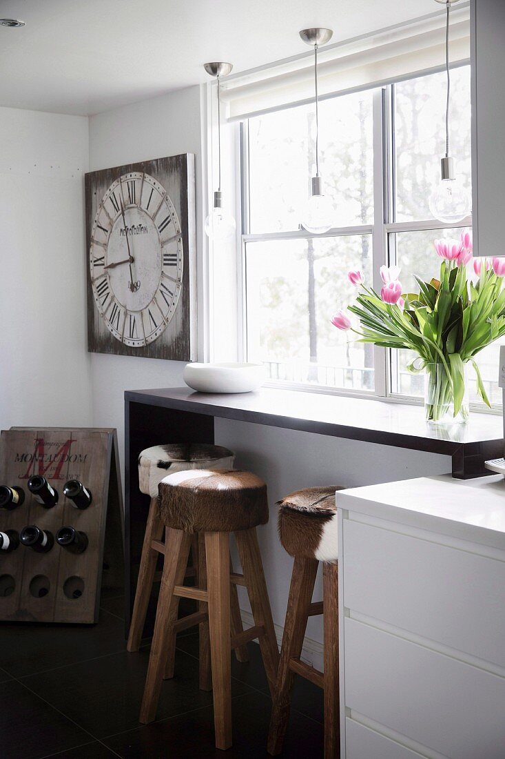 Bunch of tulips on a narrow bar in front of a window, bar stools with cowhide, in rows above pendant lights