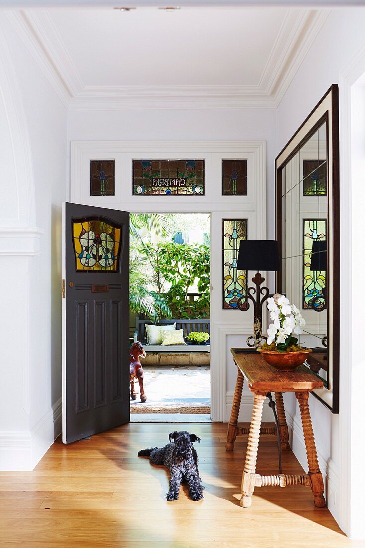 Dog lies in the entrance area with the stained glass door open