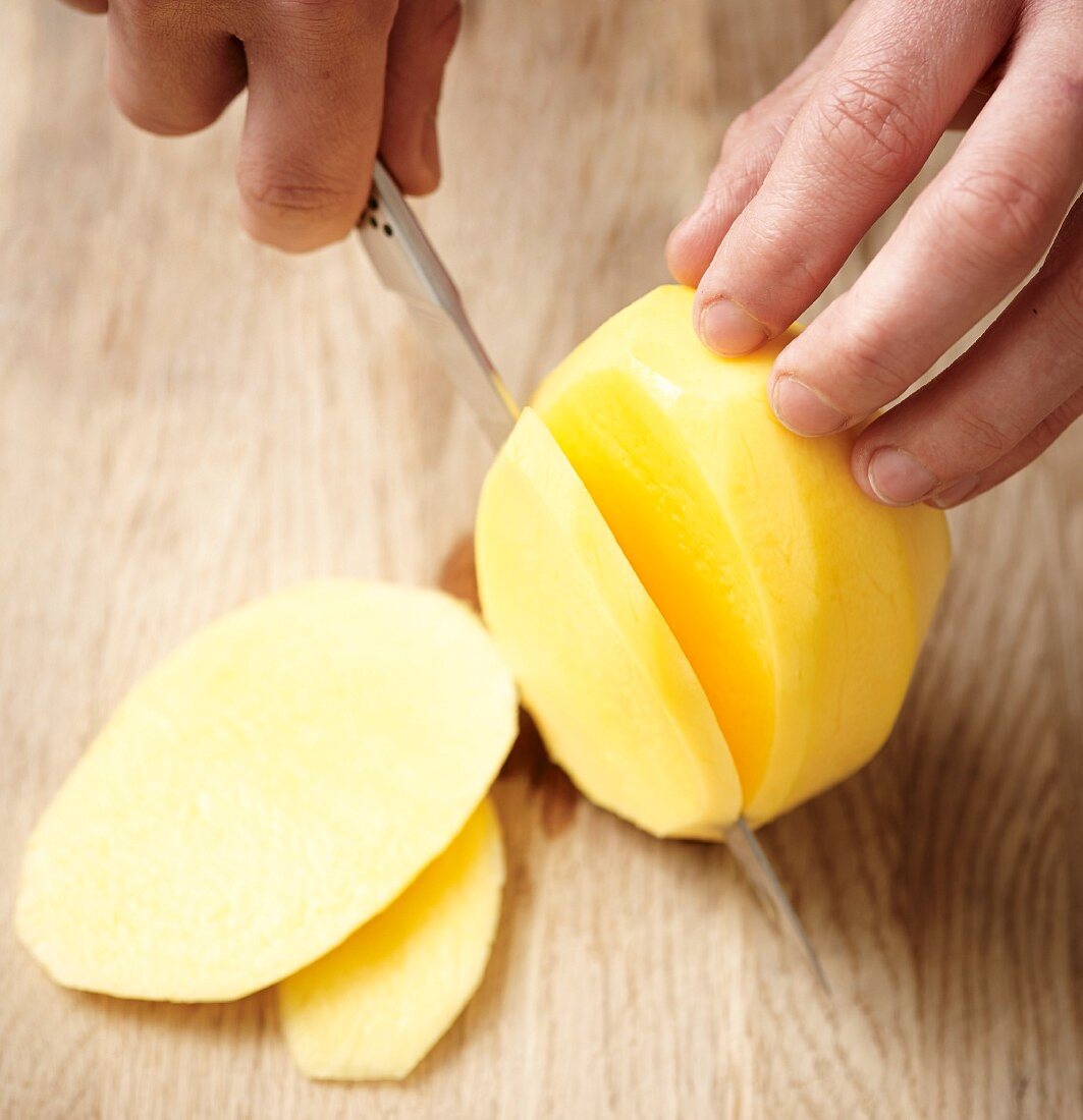 A peeled potato being sliced